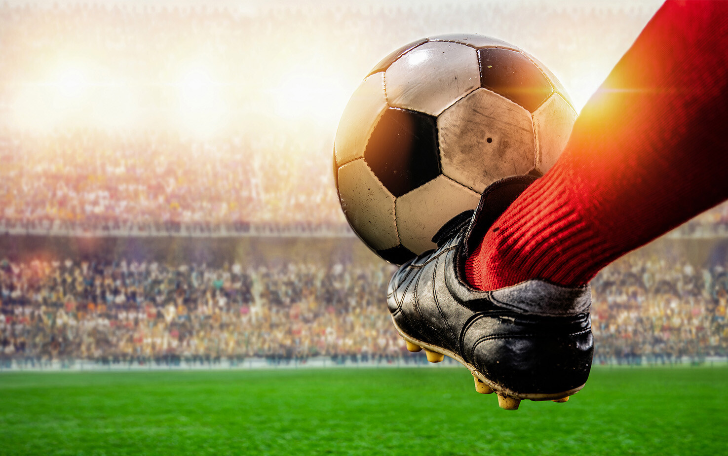 Stopa i piłka, w tle stadion.