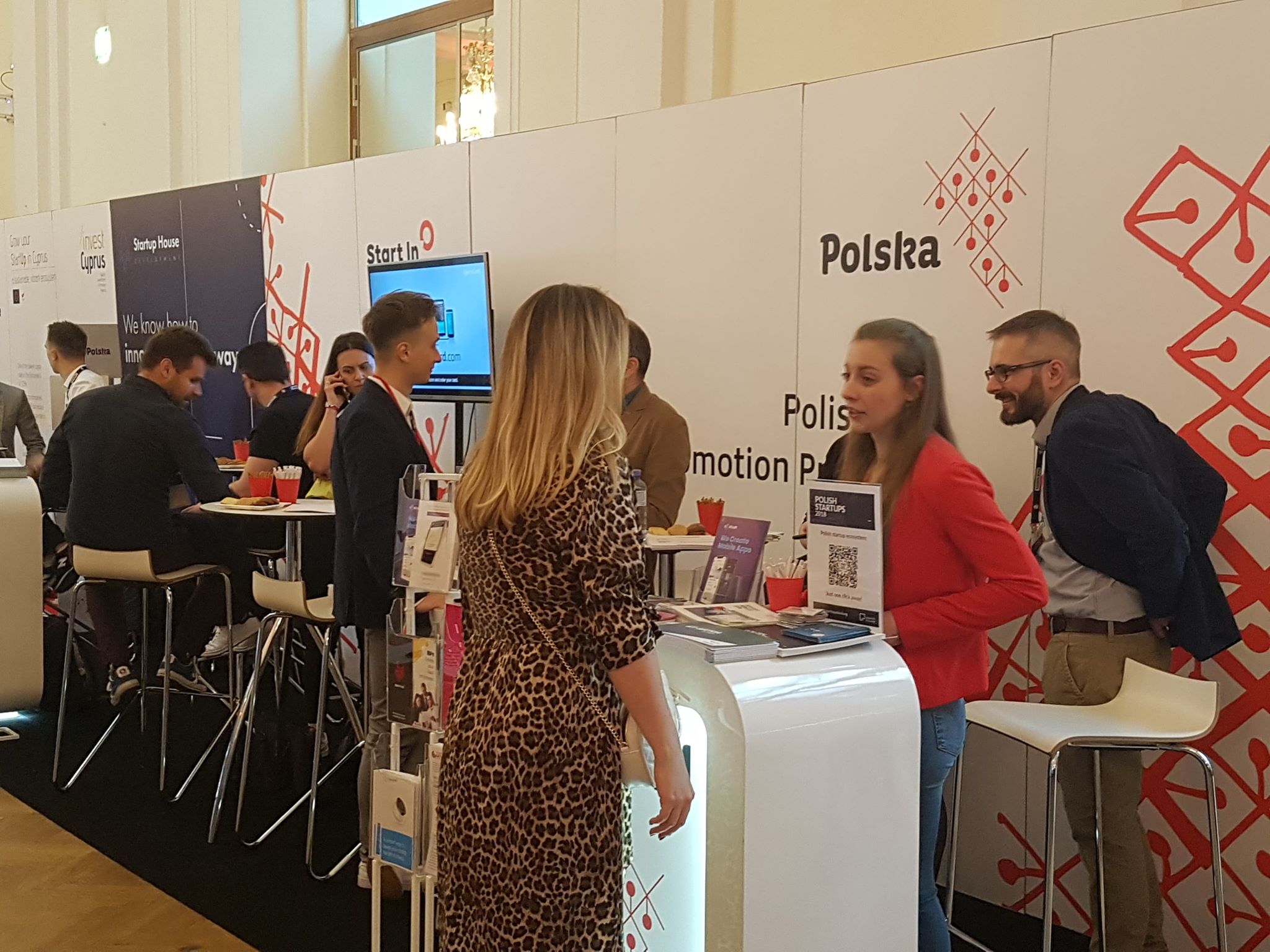 Stoisko promocyjne, przy nim rozmowy przedsiębiorców i ekspertów