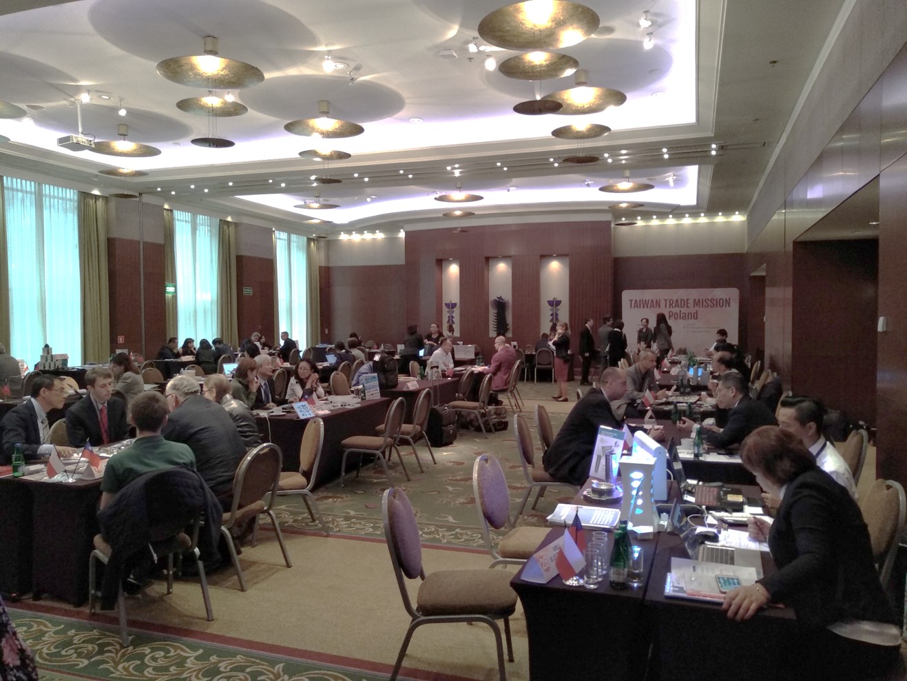 Ludzie w różnym wieku siedzą licznie przy stolikach w dużej sali