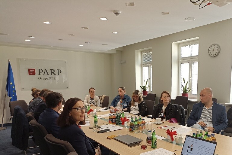 ludzie siedzą przy stole konferencyjnym i rozmawiają