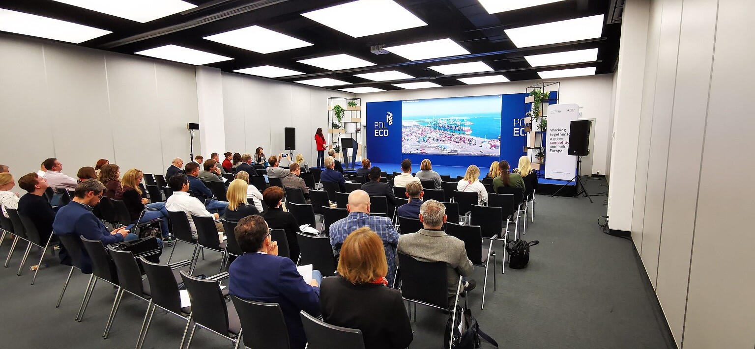 Ludzie siedzą na sali i patrzą się w telebim