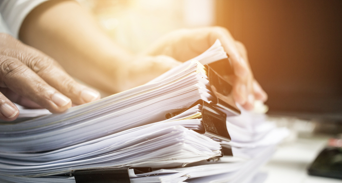 Dłonie trzymają gruby plik z dokumentami