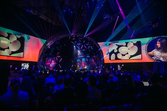 Widok na dużą salę konferencyjną z publicznością i ludźmi na scenie