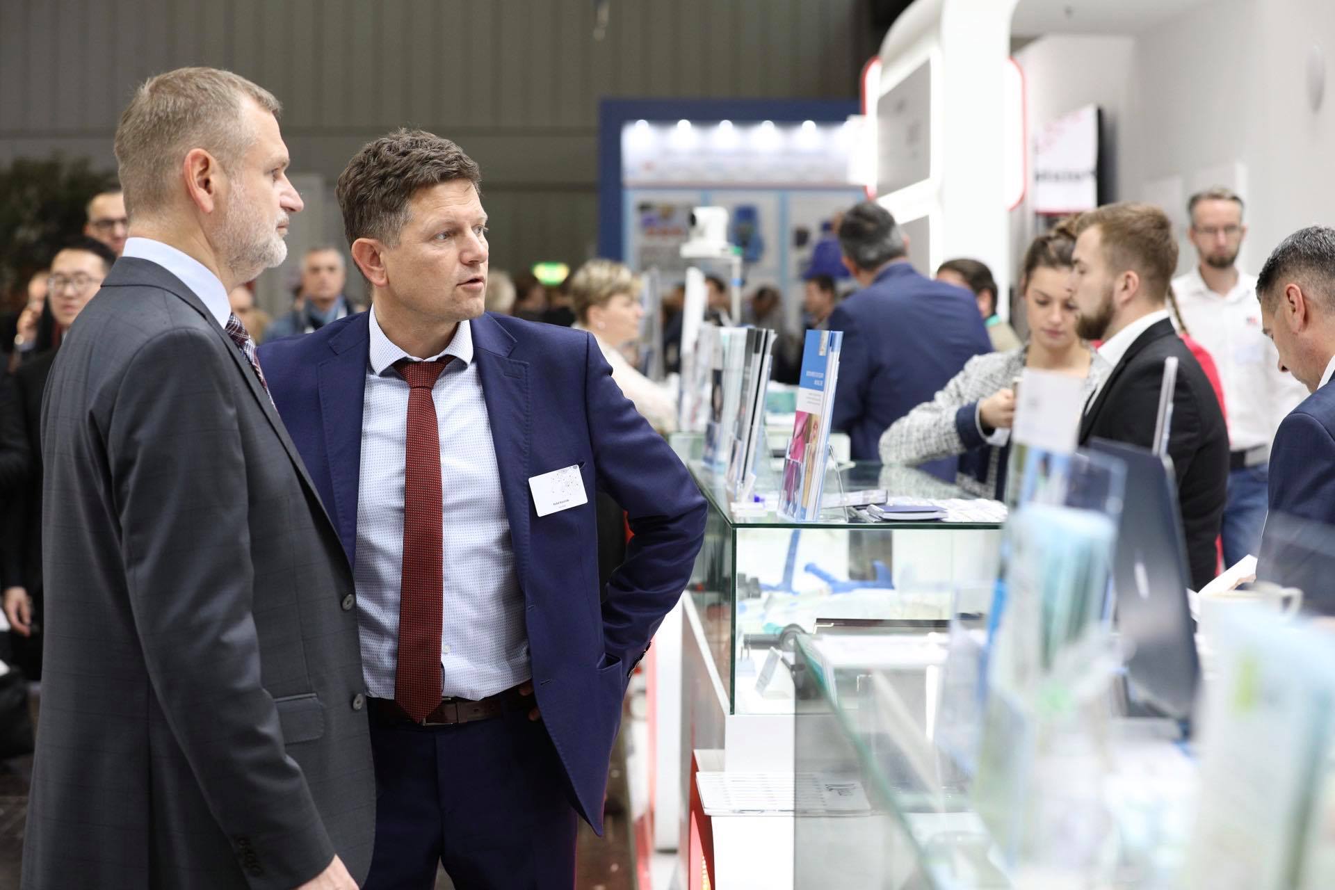 Dwóch mężczyzn stojących przed stoiskiem na targach Dwóch mężczyzn stojących przed stoiskiem na targach