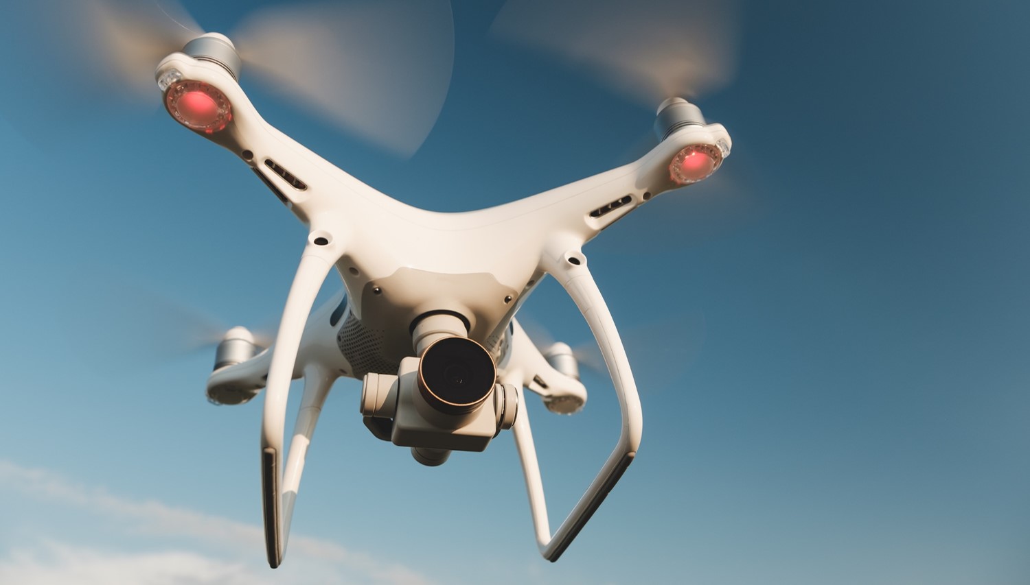 Biały dron latający po bezchmurnym niebie. 