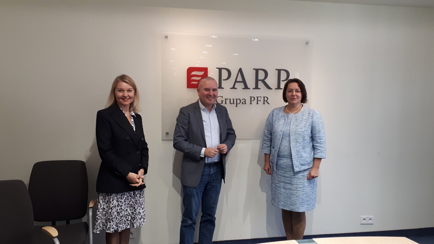 Dwie kobiety i mężczyzna pomiędzy nimi pozują do zdjęcia na tle napisu PARP