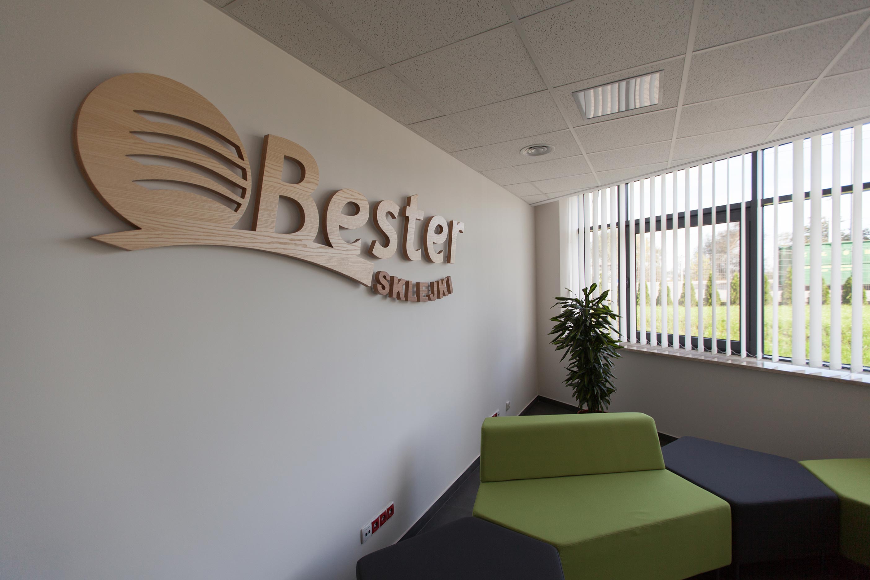 Widok pokoju z szyldem na ścianie Bester i zielonym fotelem w tle