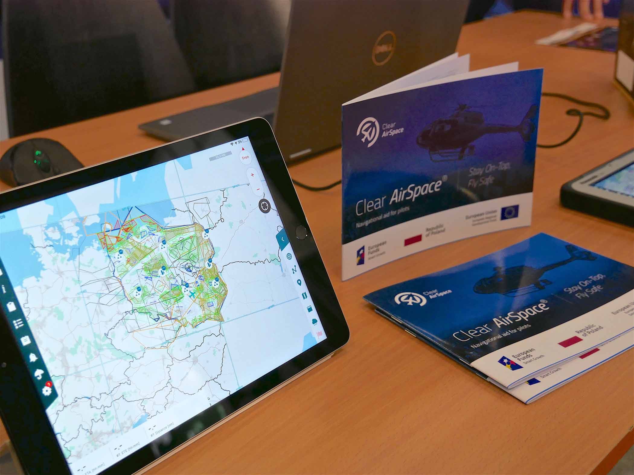 Zdjęcie biurka z tabletem i wyświetloną mapą, obok położone foldery firmy Ab tech