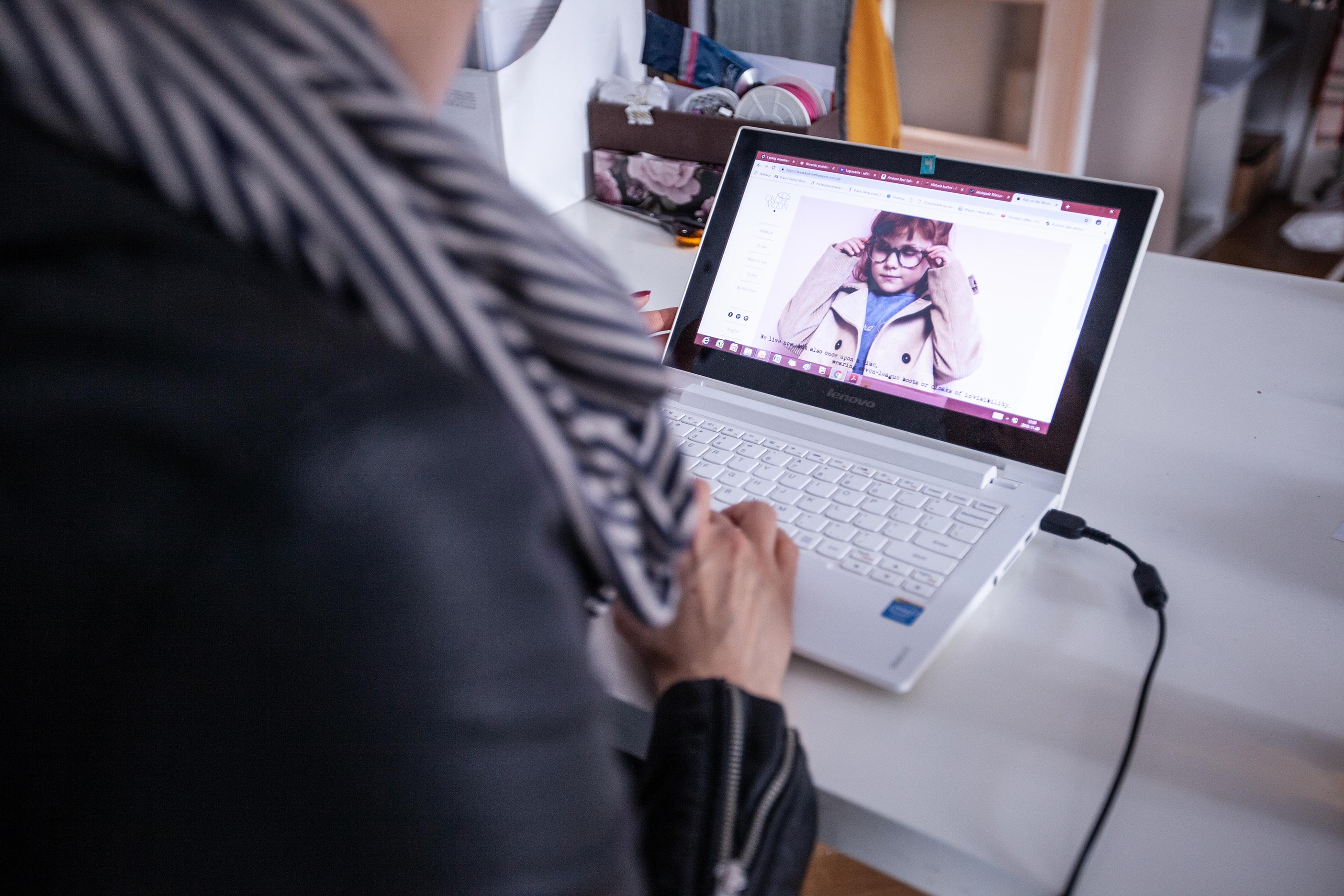 Widok osoby trzymającej notebook z wyświetloną stroną sklepu z ubraniami