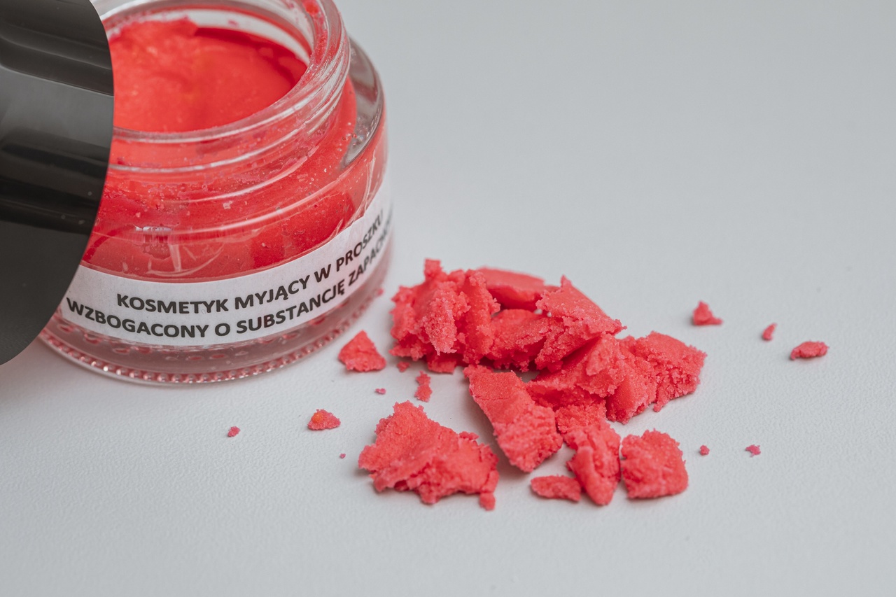 Otwarty słiczek z czerwonym proszkiem, stojący na blacie