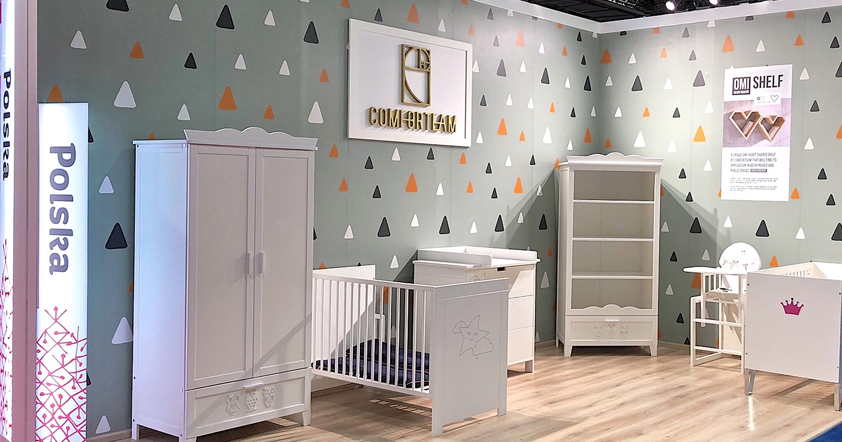 Widok stoiska targowego z meblami do pokoju dziecięcego: szafa, ł&oacute;żeczko, przewijak