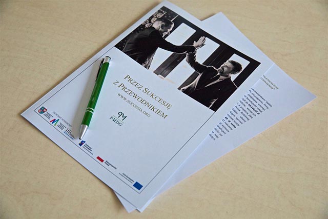 Widok biurka, stołu, na kt&oacute;rym połozona jest kartka z napisem "Przez sukcesję z przewodnikiem"